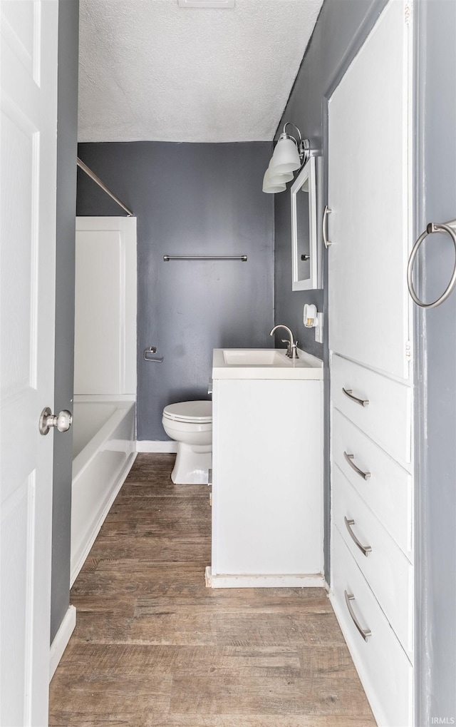 full bathroom featuring tub / shower combination, hardwood / wood-style floors, vanity, a textured ceiling, and toilet