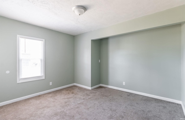 spare room with light carpet and a textured ceiling