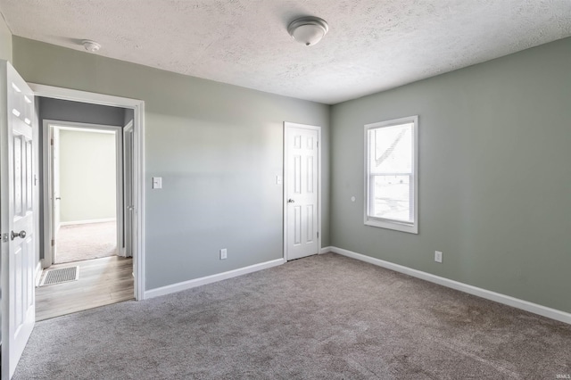 empty room with carpet flooring and a textured ceiling