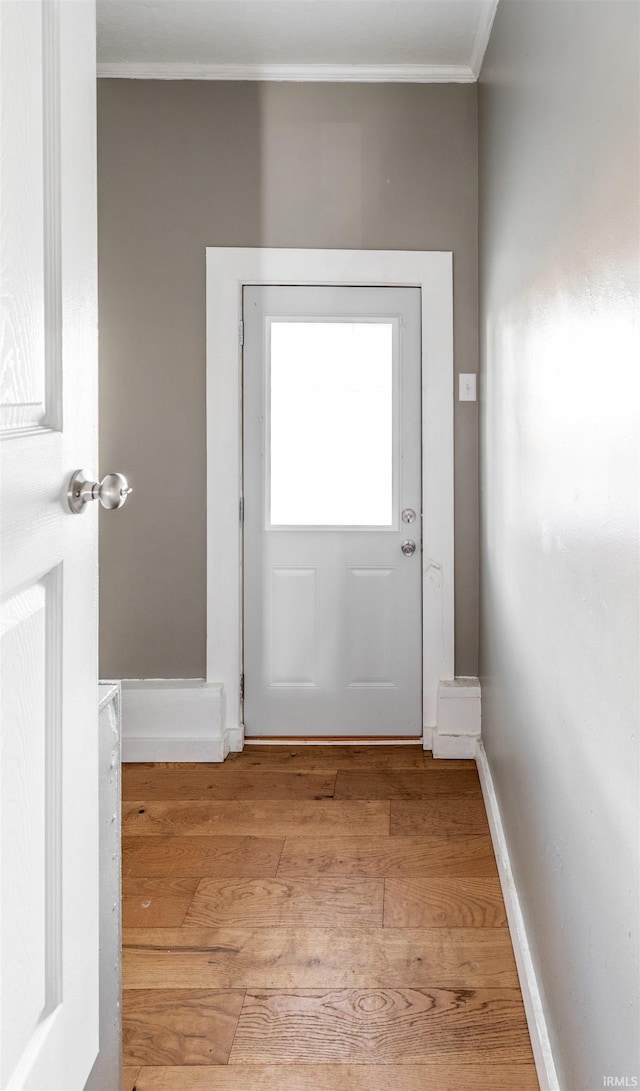 doorway to outside with crown molding and light wood-type flooring