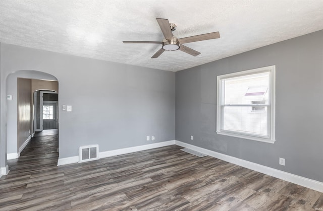 unfurnished room with ceiling fan, dark wood-type flooring, and a textured ceiling