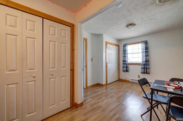 office featuring a baseboard heating unit, a textured ceiling, and light hardwood / wood-style flooring