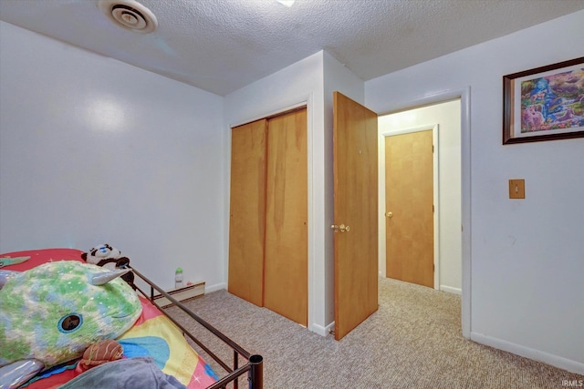 bedroom with light carpet, a closet, and a textured ceiling