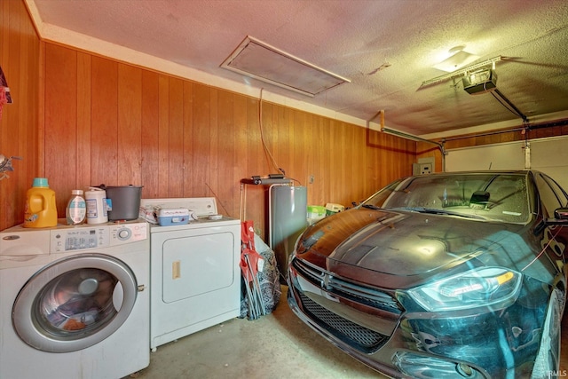 clothes washing area with washing machine and dryer, water heater, and wood walls