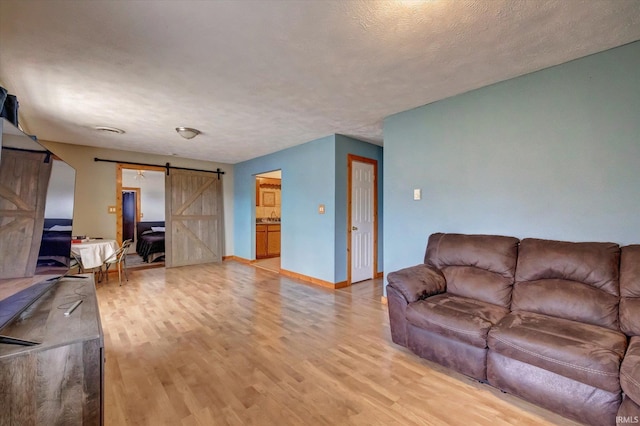 living room with light hardwood / wood-style floors, a barn door, and a textured ceiling