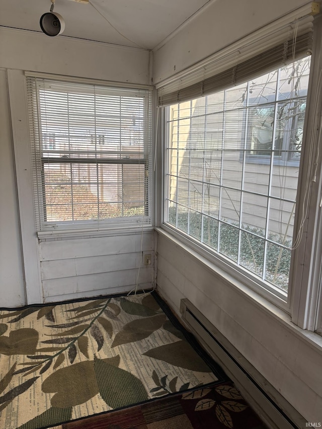 unfurnished sunroom featuring a baseboard radiator and vaulted ceiling