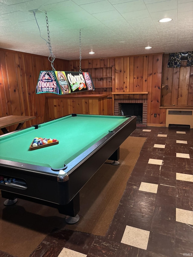 playroom with a brick fireplace, pool table, radiator heating unit, and wood walls