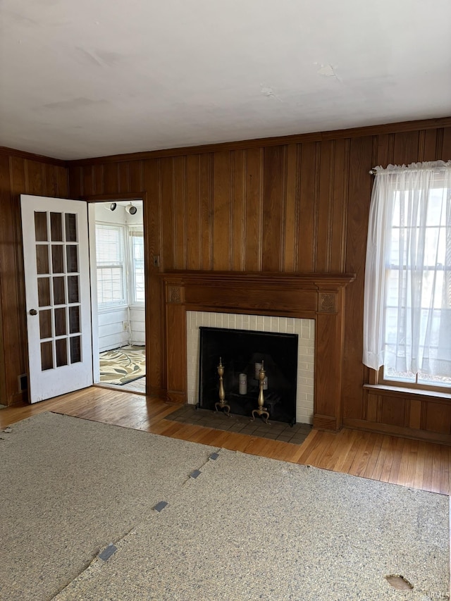 unfurnished living room with a brick fireplace, light hardwood / wood-style floors, and wood walls