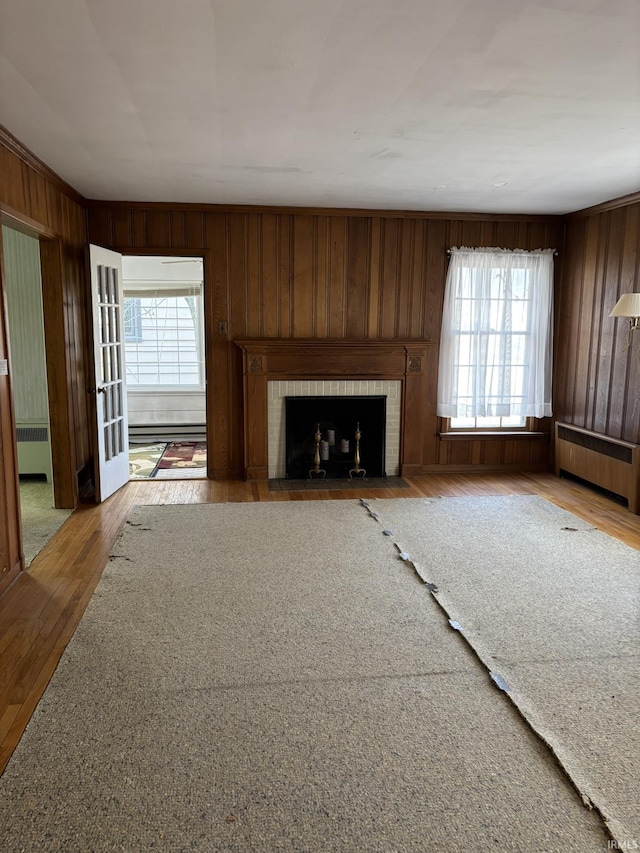 unfurnished living room featuring hardwood / wood-style floors, a wealth of natural light, radiator heating unit, and a fireplace