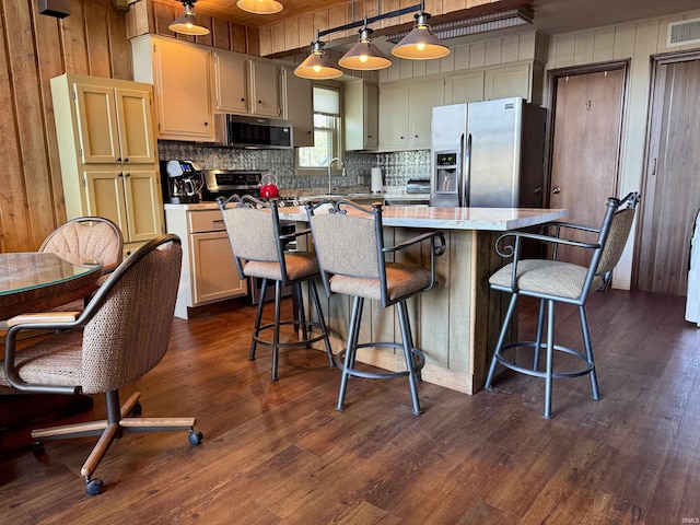 kitchen featuring appliances with stainless steel finishes, dark hardwood / wood-style flooring, a kitchen island, and decorative light fixtures