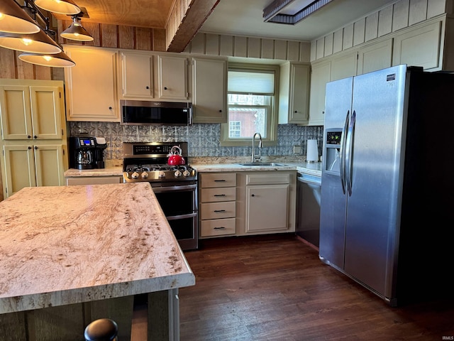 kitchen with appliances with stainless steel finishes, decorative backsplash, pendant lighting, sink, and dark hardwood / wood-style floors