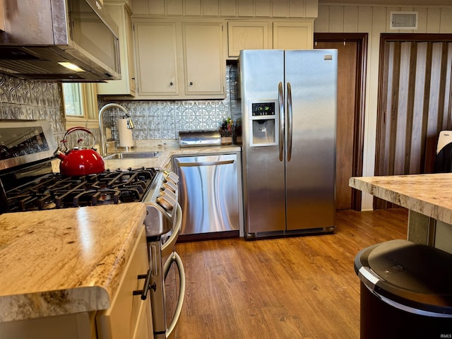 kitchen featuring sink, backsplash, appliances with stainless steel finishes, and light hardwood / wood-style floors