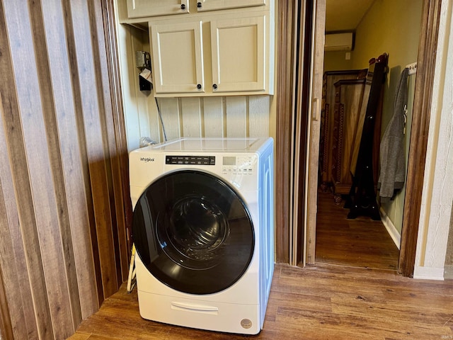 washroom with an AC wall unit, washer / clothes dryer, cabinets, and light hardwood / wood-style floors