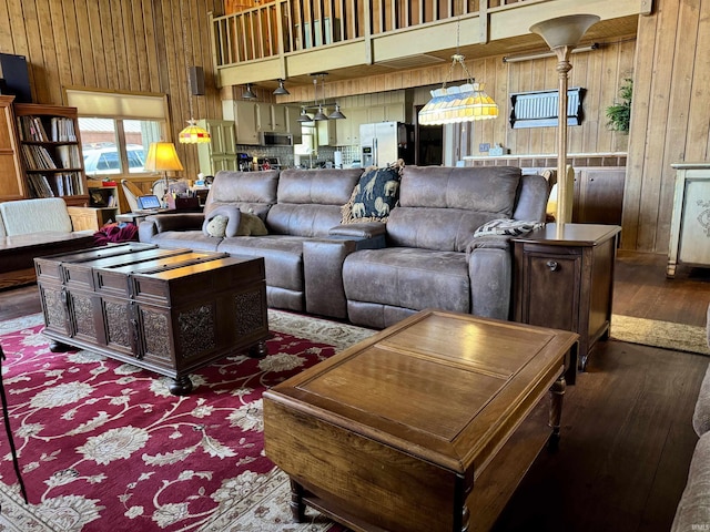 living room featuring dark hardwood / wood-style flooring, wood walls, and a towering ceiling