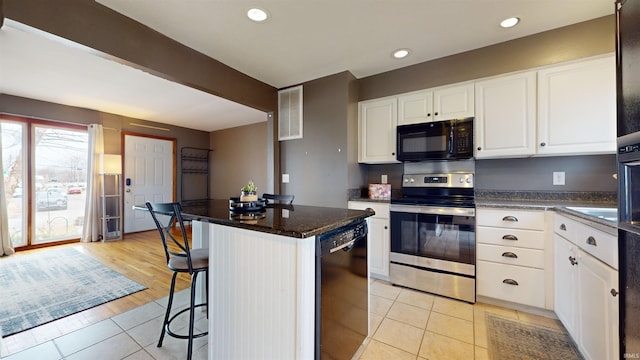 kitchen with light tile patterned flooring, a breakfast bar area, black appliances, a center island, and white cabinets