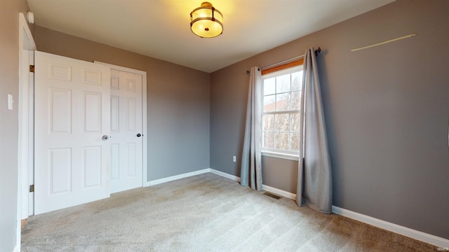 unfurnished bedroom featuring light colored carpet and a closet