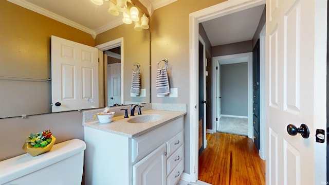 bathroom featuring ornamental molding, toilet, wood-type flooring, and vanity