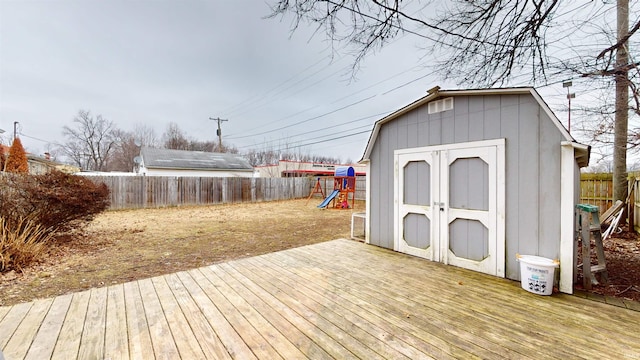 wooden terrace featuring a playground and a storage shed