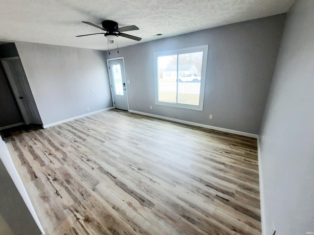 spare room with ceiling fan, light hardwood / wood-style flooring, and a textured ceiling