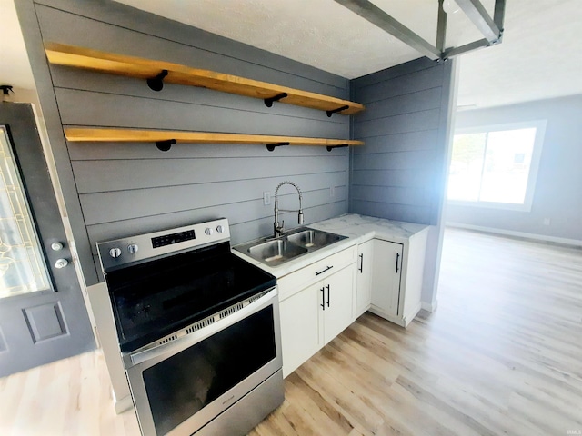 kitchen featuring sink, light hardwood / wood-style flooring, white cabinets, and stainless steel electric range