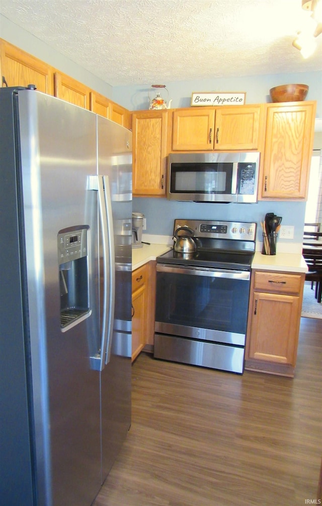 kitchen with stainless steel appliances, dark hardwood / wood-style floors, and a textured ceiling