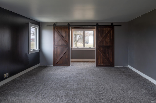 carpeted empty room with a barn door