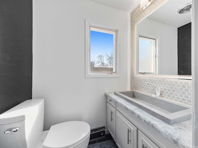 bathroom featuring tasteful backsplash, vanity, and toilet