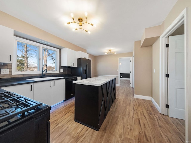 kitchen featuring sink, tasteful backsplash, a kitchen island, white cabinets, and black appliances