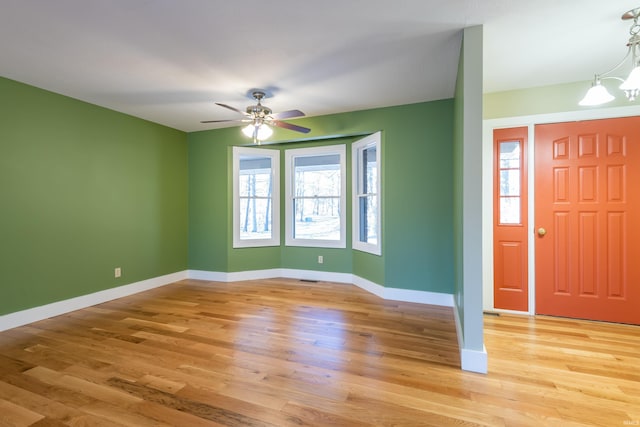 entryway with ceiling fan with notable chandelier, plenty of natural light, and light hardwood / wood-style floors