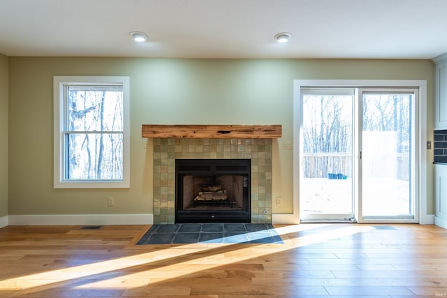 unfurnished living room featuring a tile fireplace and light hardwood / wood-style floors