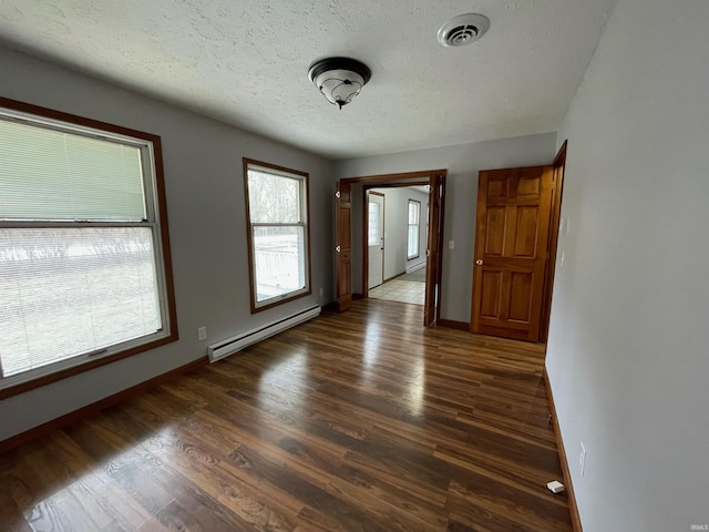 spare room featuring dark hardwood / wood-style floors, a textured ceiling, and baseboard heating