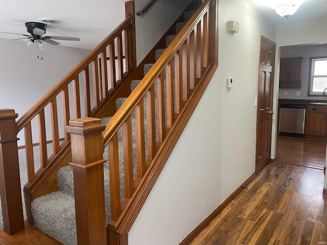 staircase featuring sink, wood-type flooring, and ceiling fan