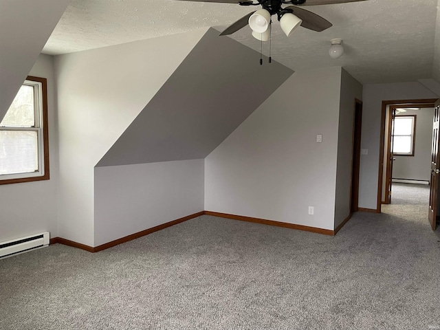 additional living space featuring carpet, vaulted ceiling, a textured ceiling, and a baseboard heating unit