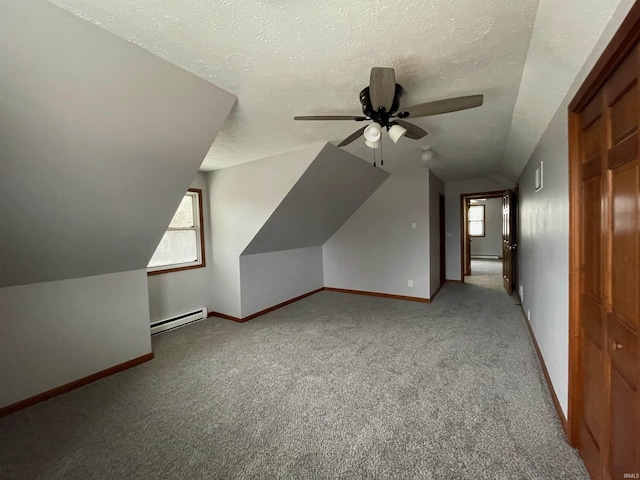 additional living space featuring lofted ceiling, a baseboard radiator, a textured ceiling, and plenty of natural light