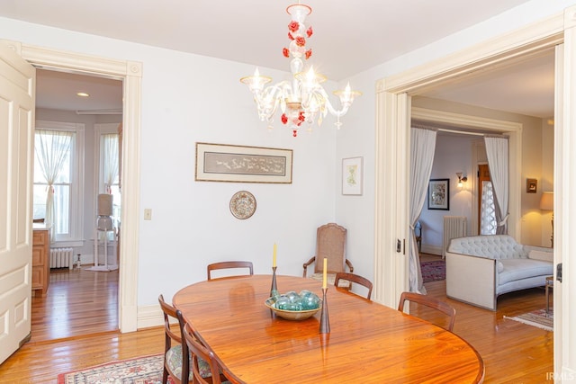 dining space featuring a chandelier, radiator heating unit, and light wood-type flooring