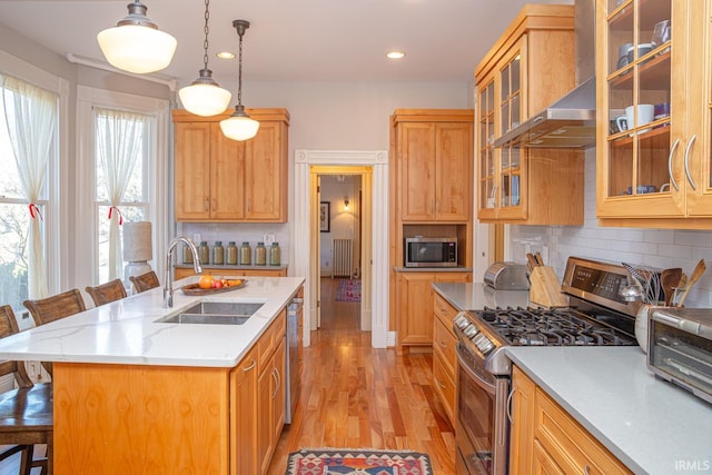 kitchen with pendant lighting, sink, a kitchen breakfast bar, stainless steel appliances, and a center island with sink