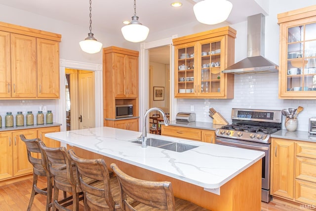 kitchen with sink, stainless steel appliances, a breakfast bar, and wall chimney exhaust hood