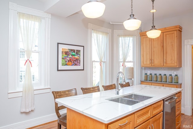 kitchen with decorative light fixtures, dishwasher, sink, a kitchen breakfast bar, and a center island with sink