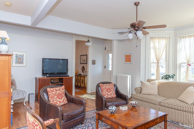 living room with ceiling fan, radiator heating unit, light wood-type flooring, and plenty of natural light