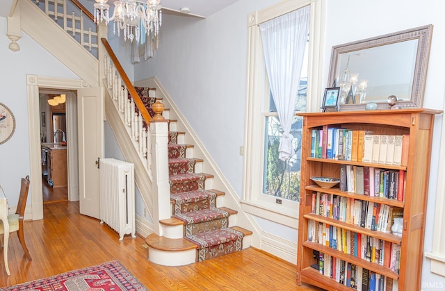 staircase with hardwood / wood-style flooring, radiator, and a chandelier