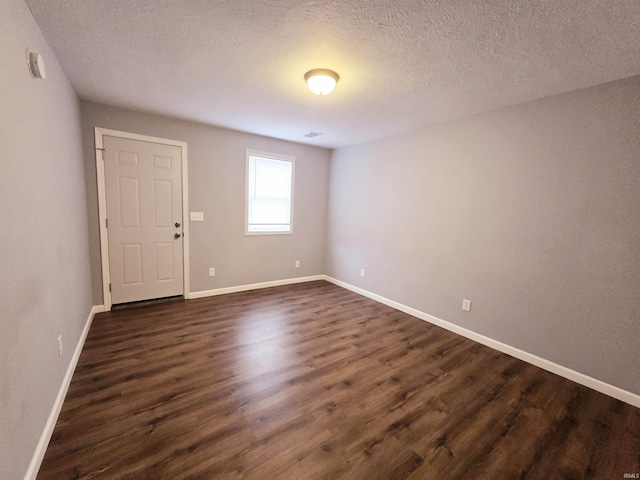 empty room with dark hardwood / wood-style floors and a textured ceiling