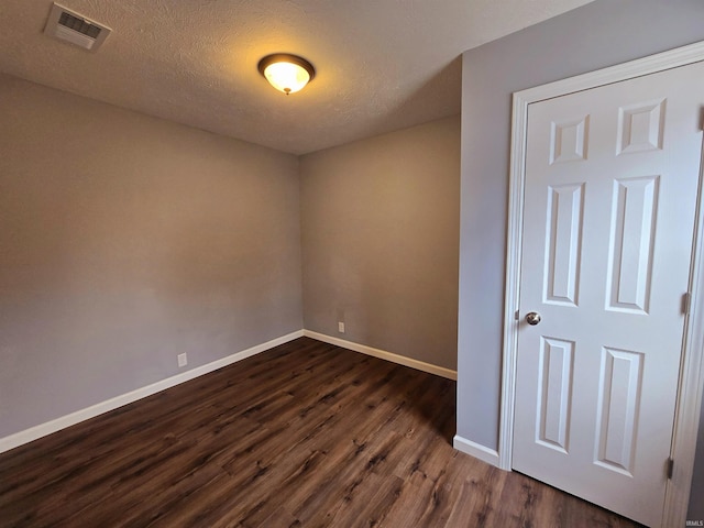 empty room featuring dark wood-type flooring and a textured ceiling