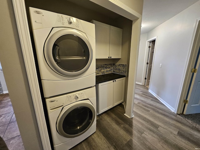 laundry area with stacked washer and dryer, dark hardwood / wood-style floors, and cabinets