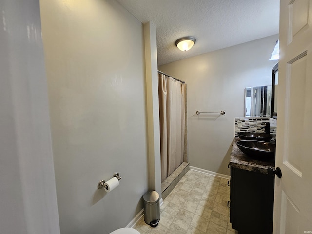 bathroom with vanity, toilet, curtained shower, and a textured ceiling