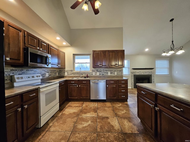 kitchen featuring sink, vaulted ceiling, appliances with stainless steel finishes, pendant lighting, and decorative backsplash