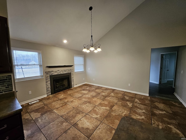 unfurnished living room featuring a tile fireplace, plenty of natural light, high vaulted ceiling, and a chandelier