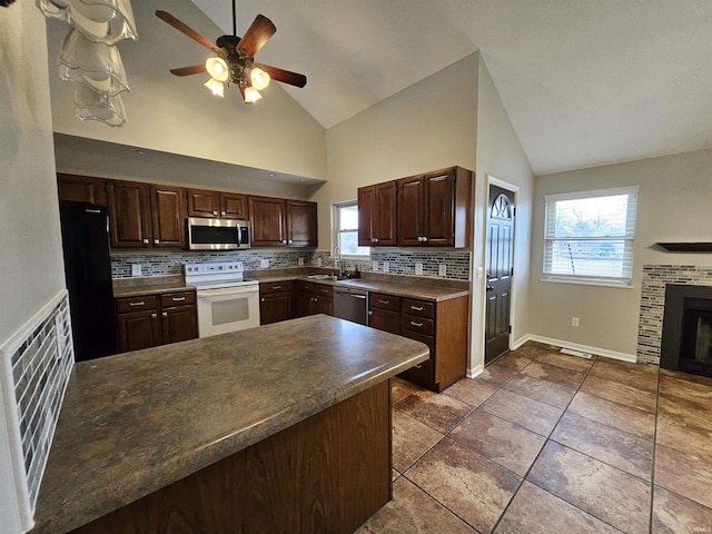 kitchen featuring dark brown cabinetry, sink, a brick fireplace, and appliances with stainless steel finishes