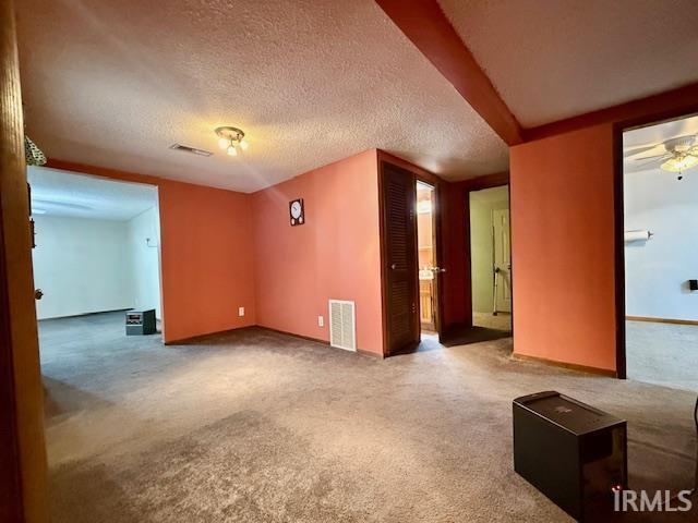 unfurnished room with a textured ceiling and carpet flooring