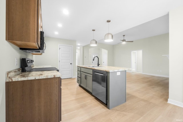 kitchen with sink, decorative light fixtures, light wood-type flooring, an island with sink, and stainless steel appliances