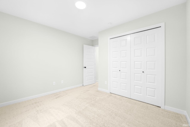 unfurnished bedroom with light carpet and a closet